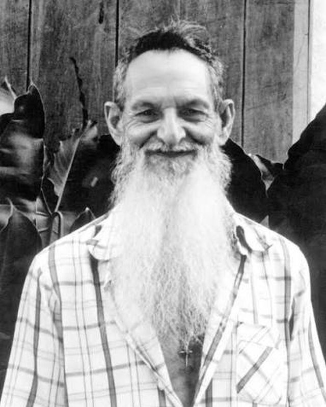 Padrinho Sebastião sorrindo, de barba longa e branca e camisa xadrez